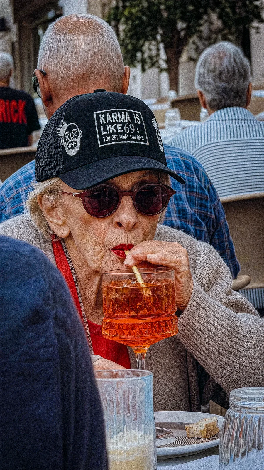 Portrait d’une femme portant une casquette noire, assise à une table de café avec une boisson.